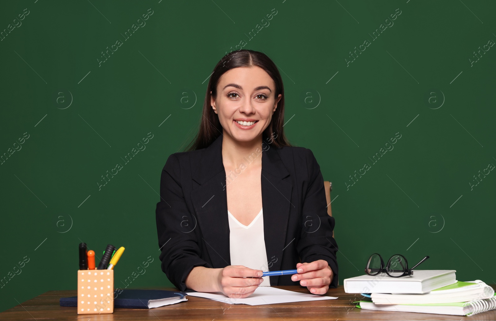 Photo of Portrait of young teacher at table against green background