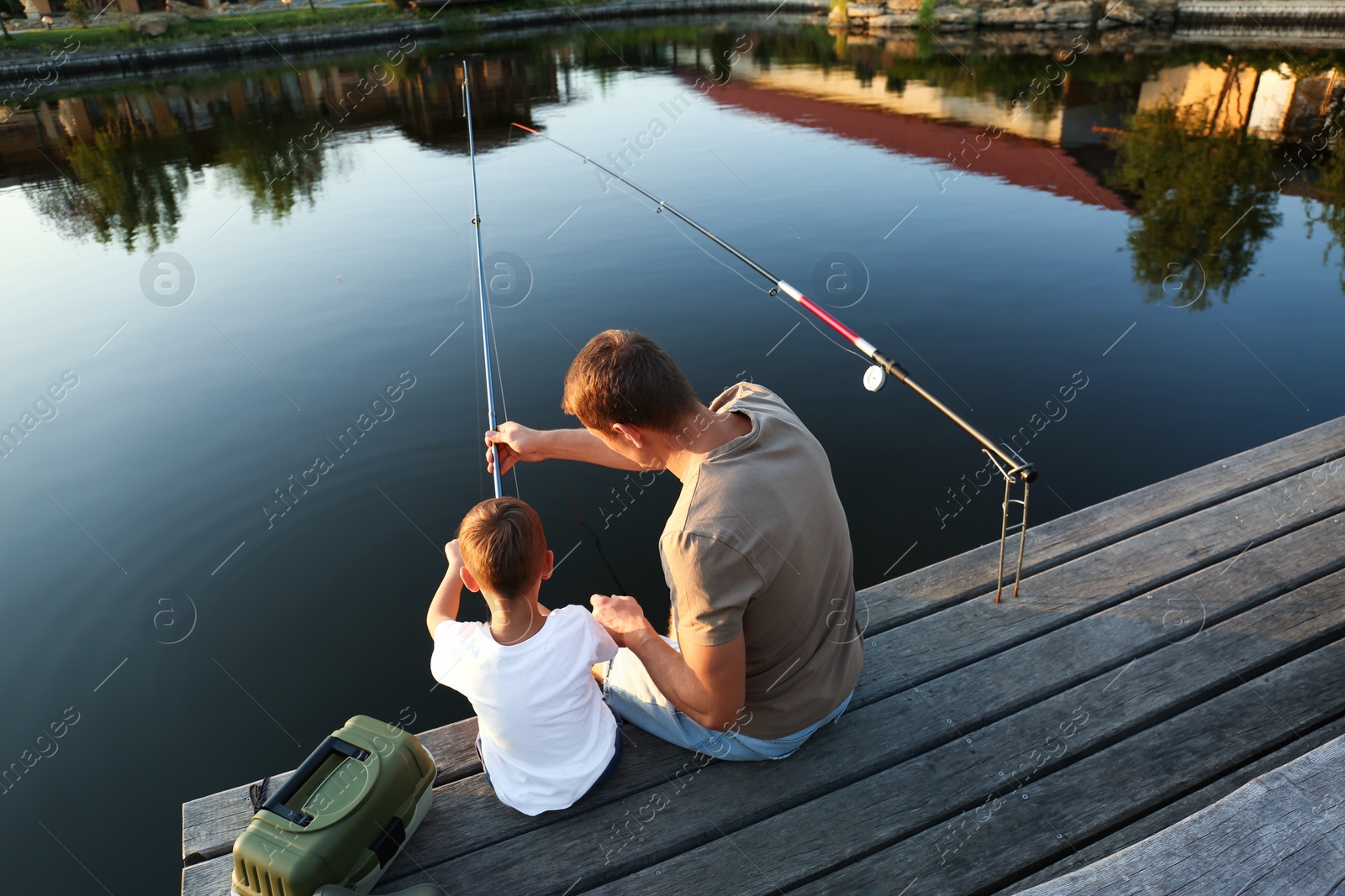 Photo of Dad and son fishing together on sunny day