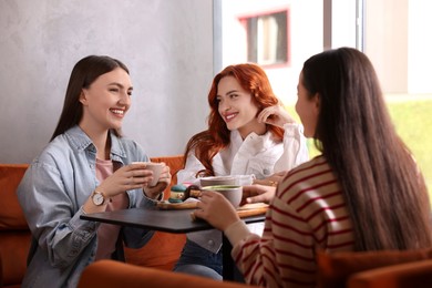 Photo of Happy friends spending time together in cafe