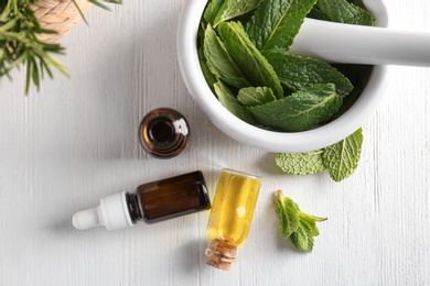 Photo of Composition with mint essential oil on white wooden background