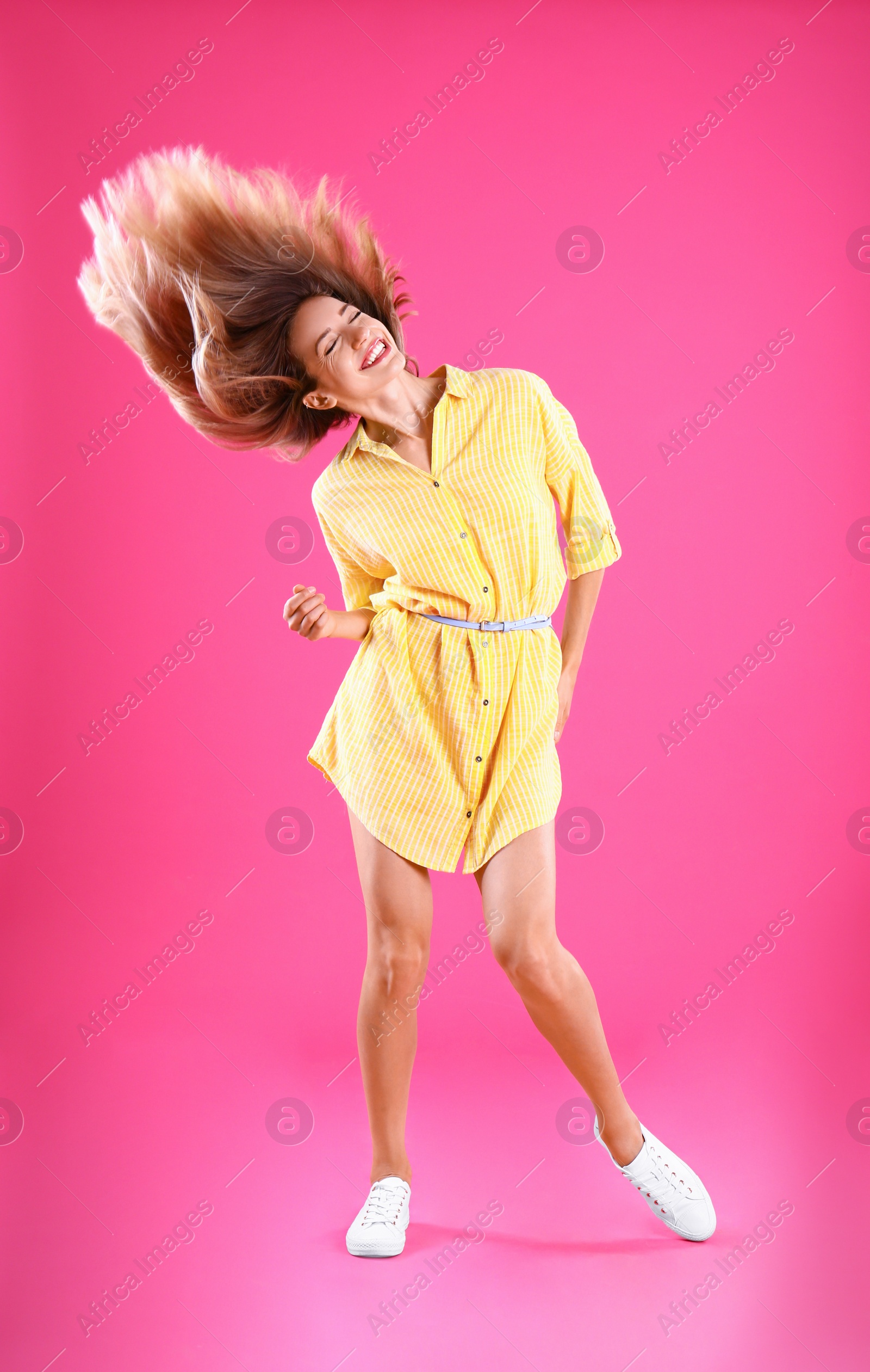 Photo of Beautiful young woman in yellow dress dancing on pink background