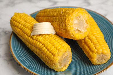 Photo of Delicious boiled corn with butter on plate, closeup