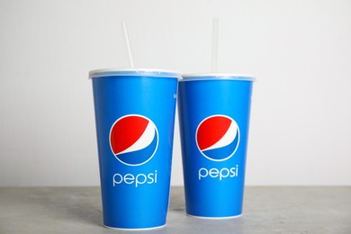 Photo of MYKOLAIV, UKRAINE - JUNE 9, 2021: Paper Pepsi cups on light grey table against white background