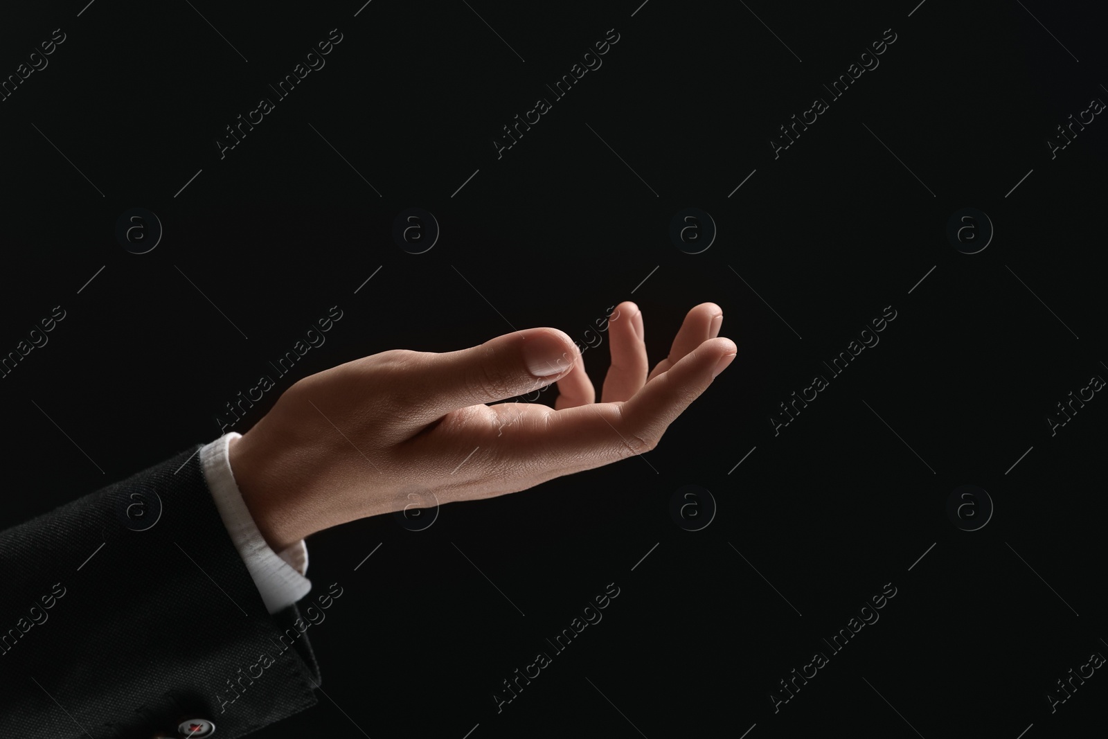 Photo of Man holding something in hand on black background, closeup. Space for text