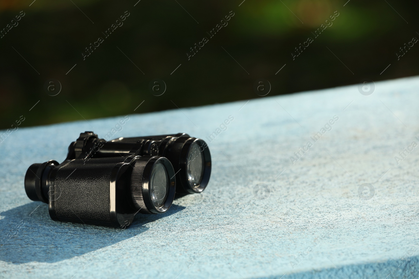 Photo of Modern binoculars on stone surface outdoors, space for text