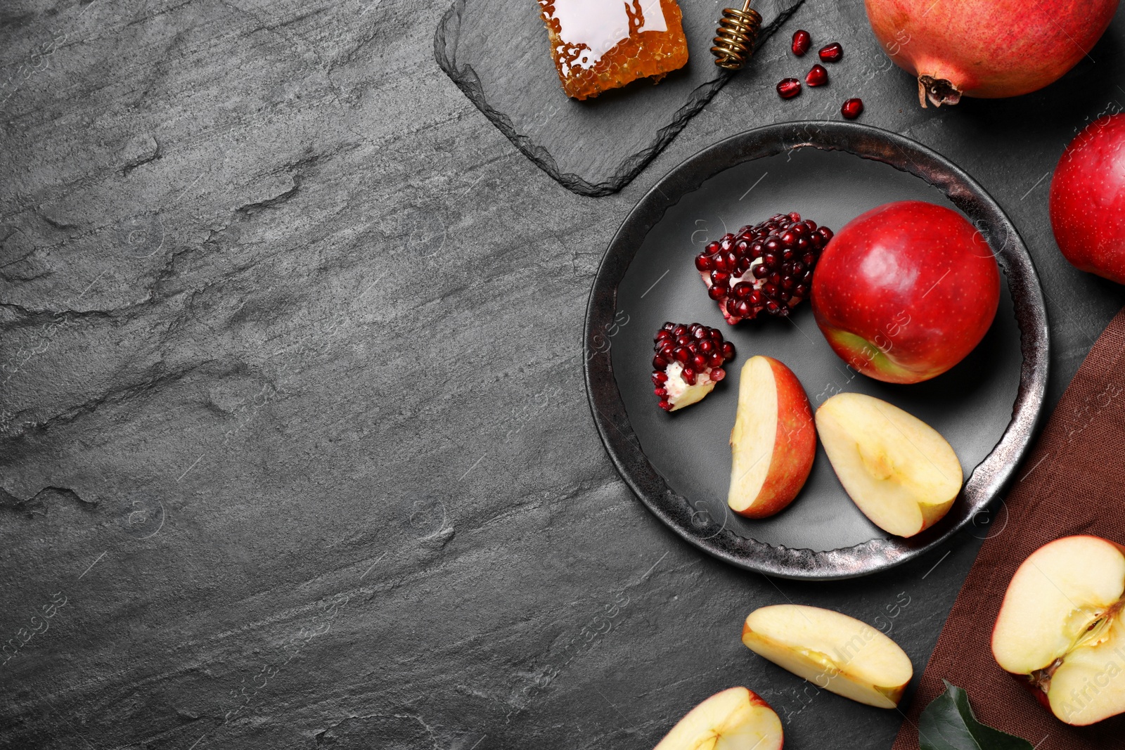 Photo of Honey, apples and pomegranates on black table, flat lay with space for text. Rosh Hashanah holiday