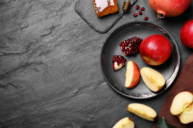 Photo of Honey, apples and pomegranates on black table, flat lay with space for text. Rosh Hashanah holiday