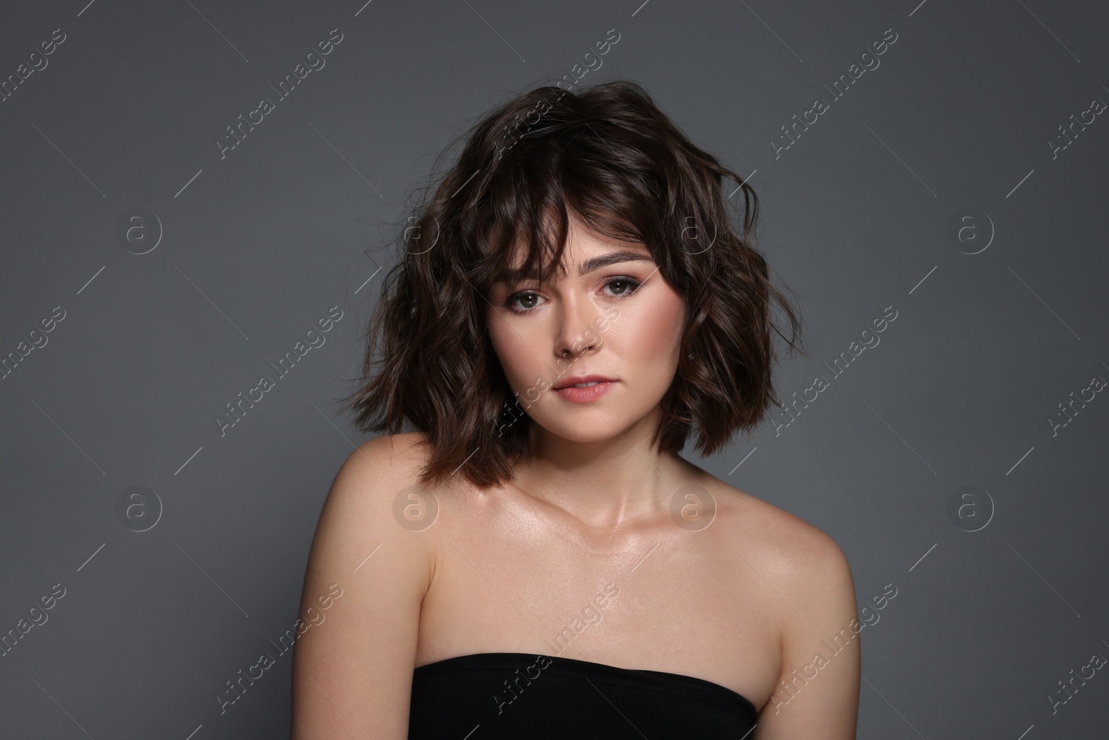 Photo of Portrait of beautiful young woman with wavy hairstyle on grey background