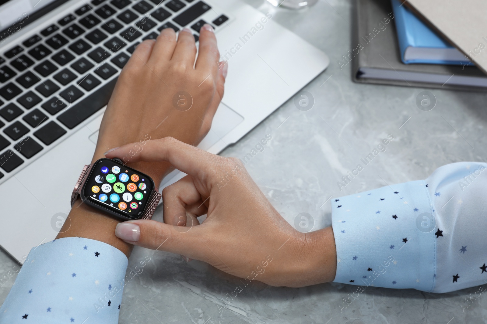 Image of MYKOLAIV, UKRAINE - SEPTEMBER 19, 2019: Woman using Apple Watch at grey table, closeup