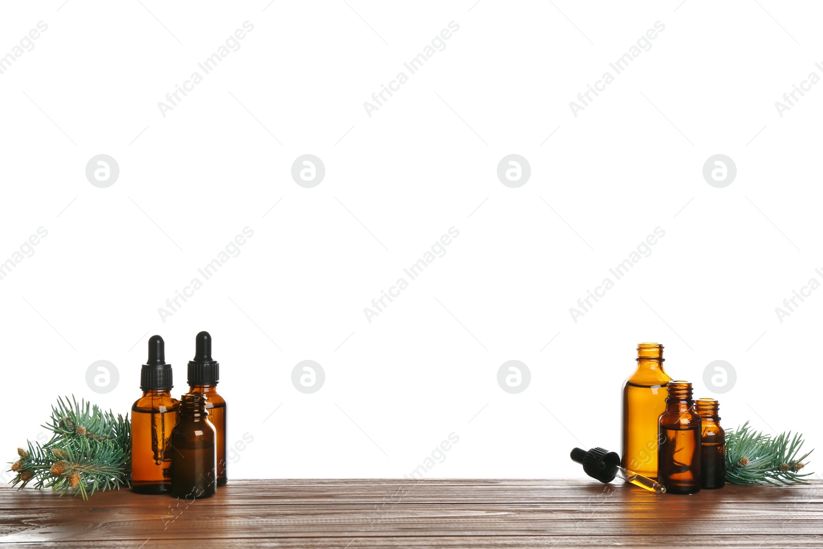 Photo of Bottles of essential oil, pipette and pine branch on table against white background