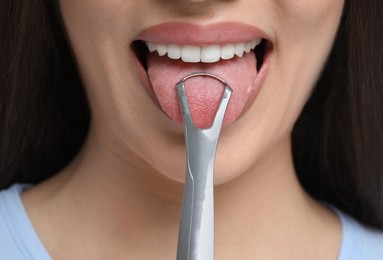 Photo of Woman brushing her tongue with cleaner, closeup