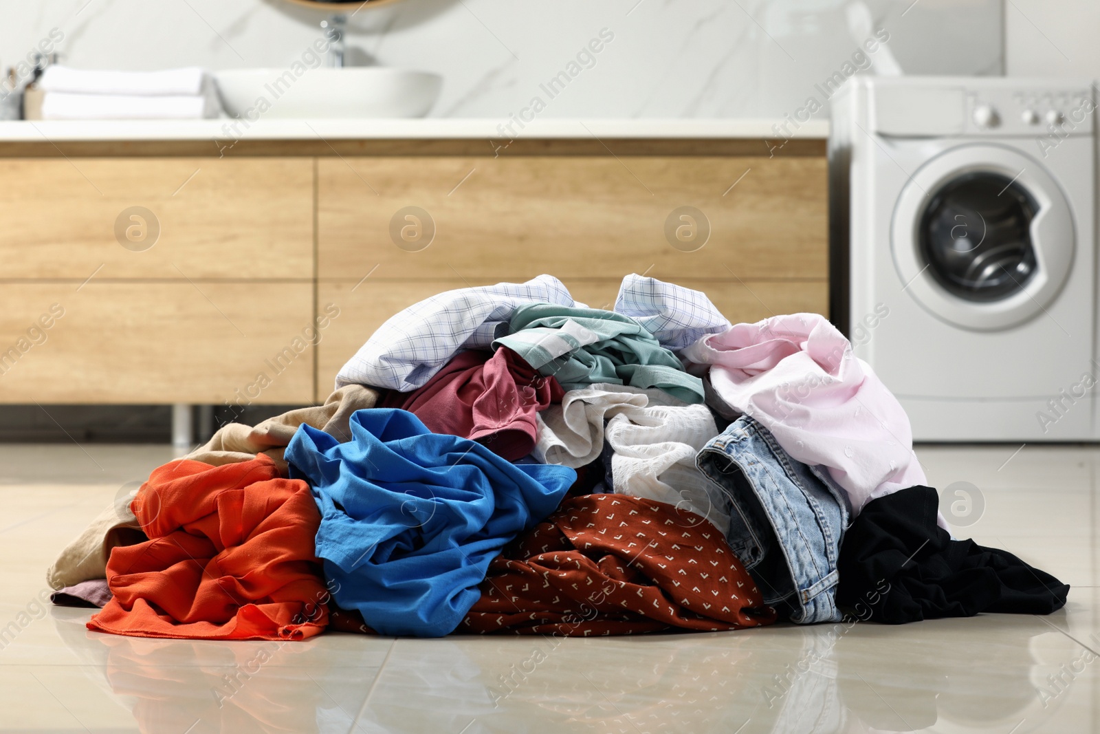 Photo of Pile of dirty clothes on floor in laundry room