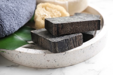 Photo of Natural tar soap on white marble table, closeup
