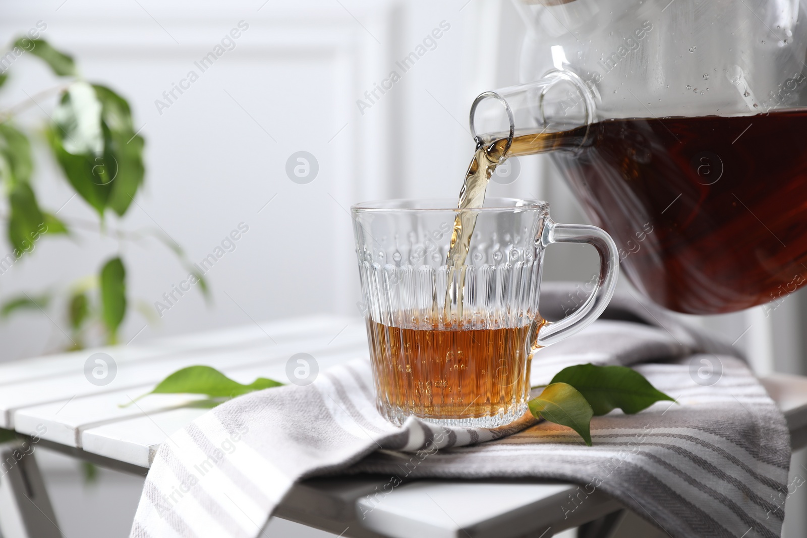 Photo of Pouring hot tea into cup on table, closeup