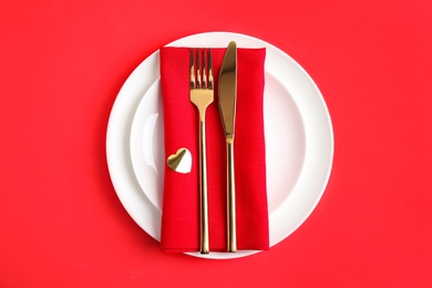 Photo of Beautiful table setting for romantic dinner on red background, top view. Valentine's day celebration