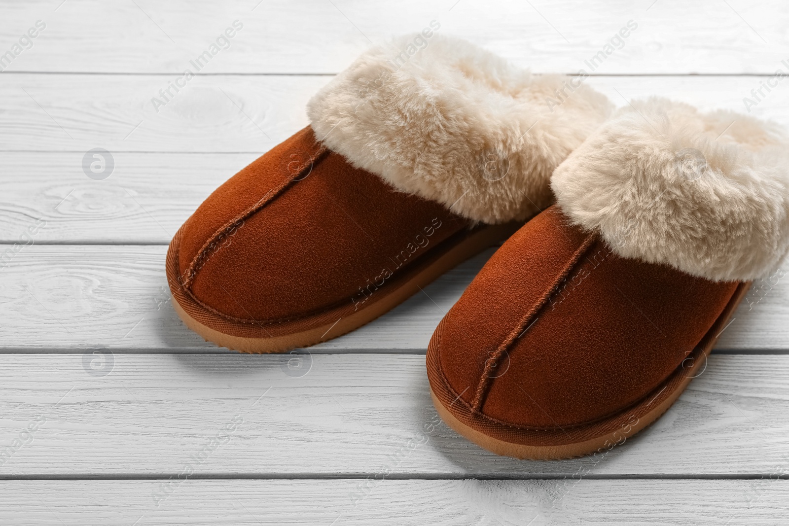 Photo of Pair of stylish soft slippers on white wooden background