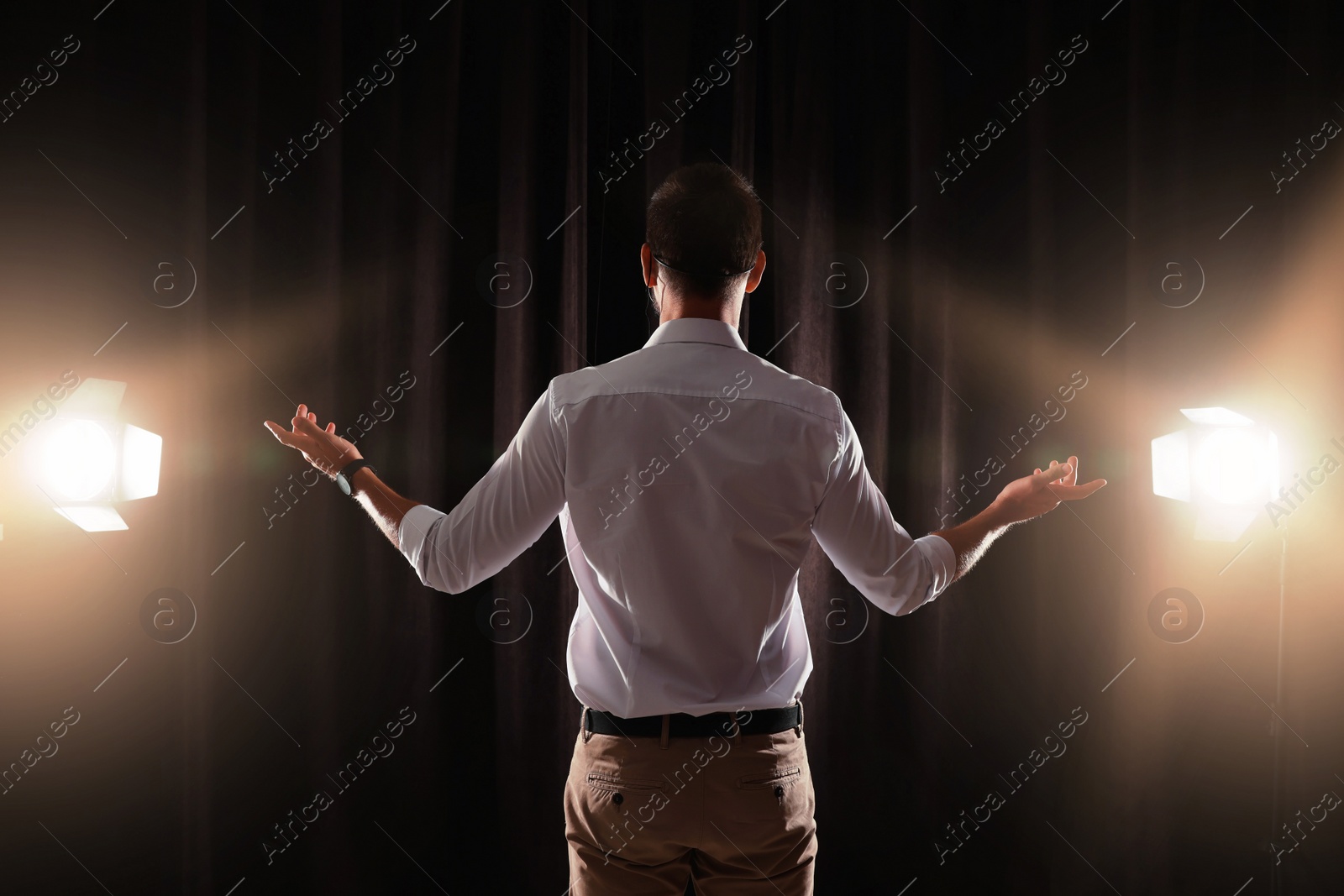 Photo of Motivational speaker with headset performing on stage, back view