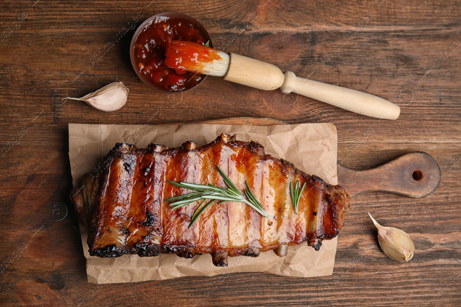 Photo of Tasty grilled ribs with sauce on wooden table, flat lay