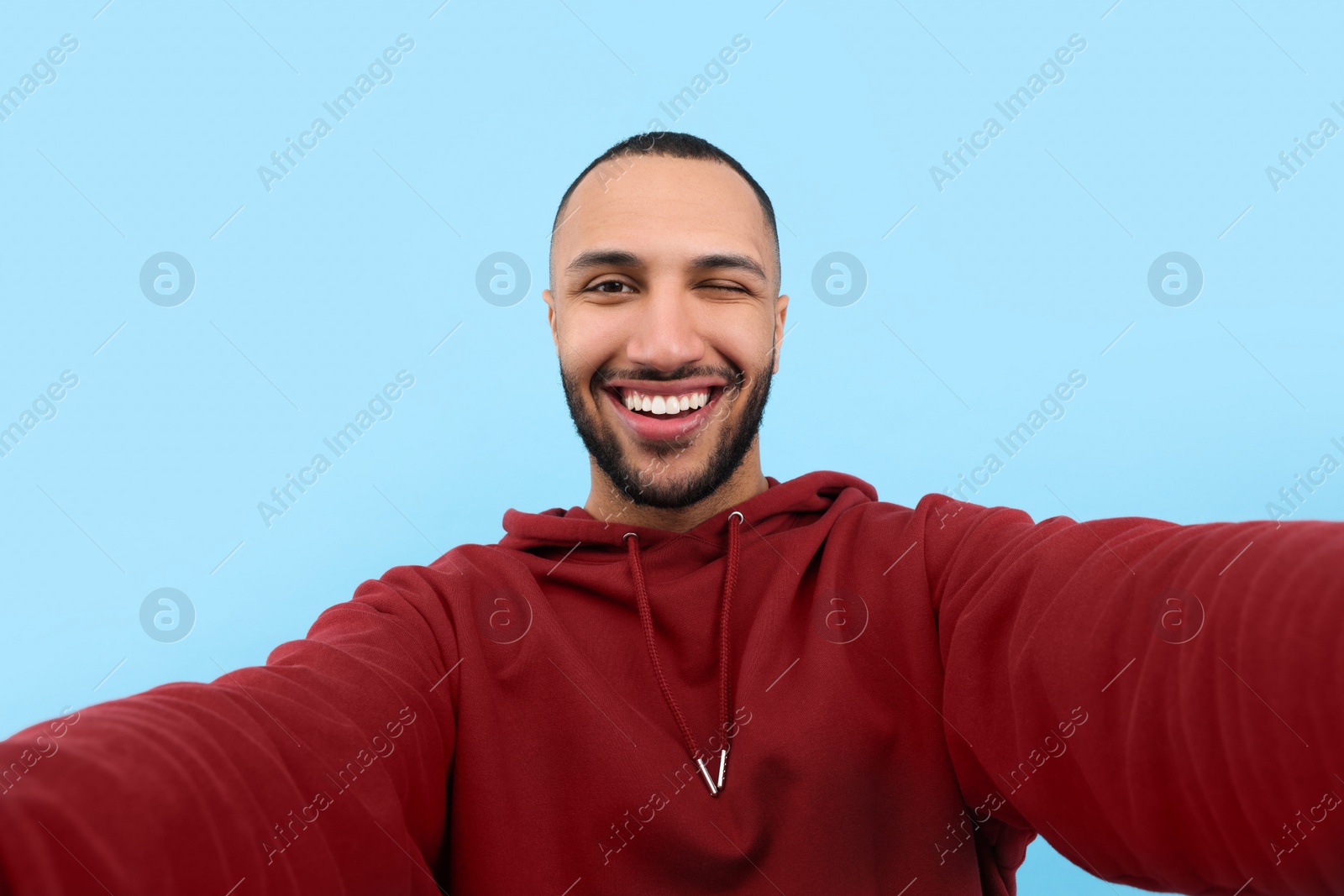 Photo of Smiling young man taking selfie on light blue background