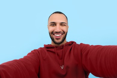 Photo of Smiling young man taking selfie on light blue background