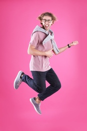 Photo of Young man playing air guitar on color background