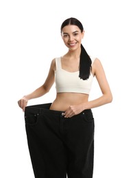 Photo of Happy young woman wearing big jeans after weight loss on white background