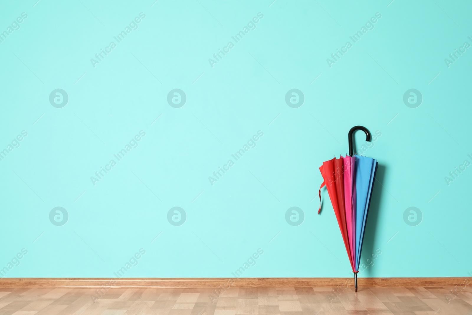 Photo of Beautiful umbrella on floor near color wall with space for design