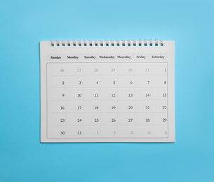 Paper calendar on light blue background, top view