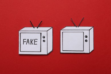 Paper TVs with word Fake and empty screen on red background, flat lay. Information warfare concept