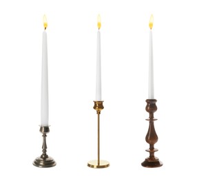 Set of different stylish candlesticks with burning candles on white background