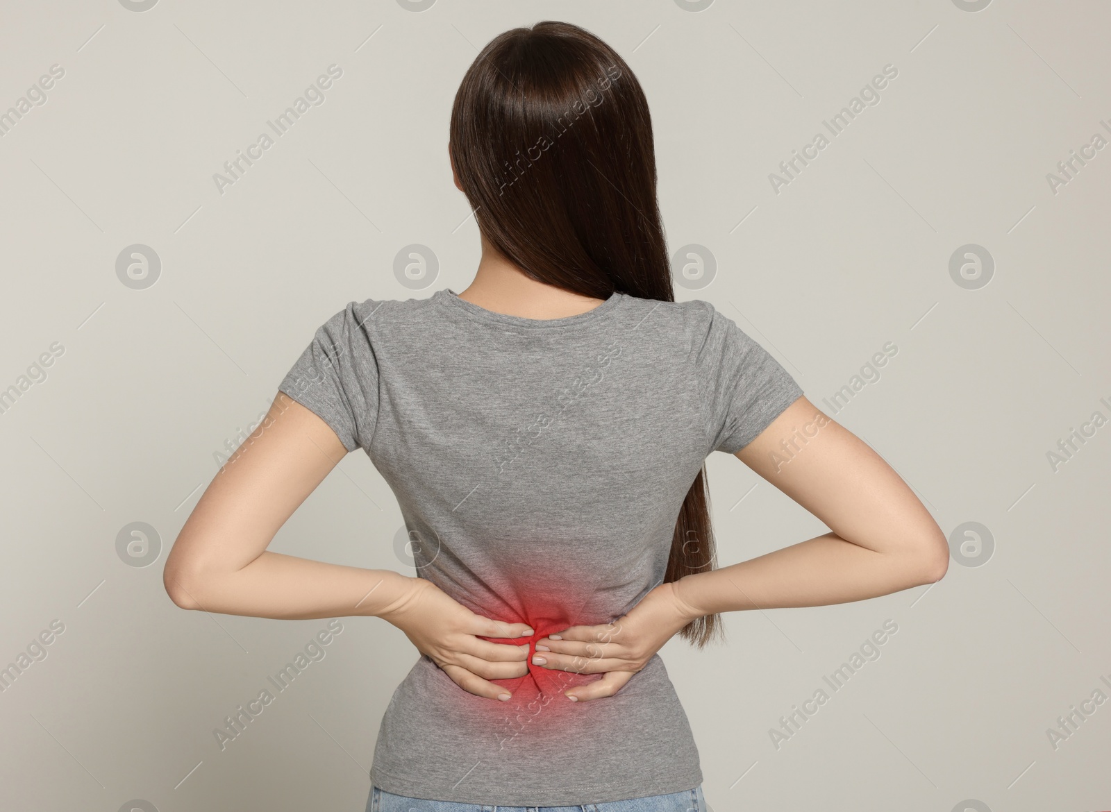 Image of Woman suffering from pain in lower back on light background