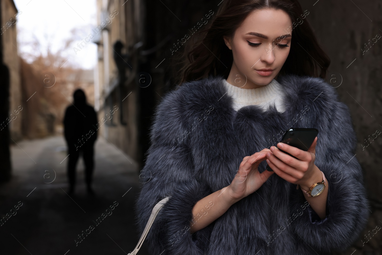 Photo of Man stalking young woman with phone in alley
