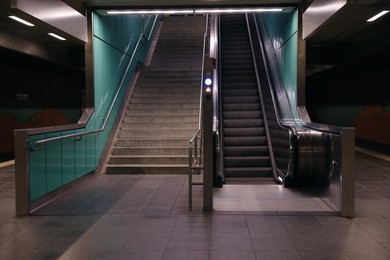 Modern escalator and stairs in dark subway