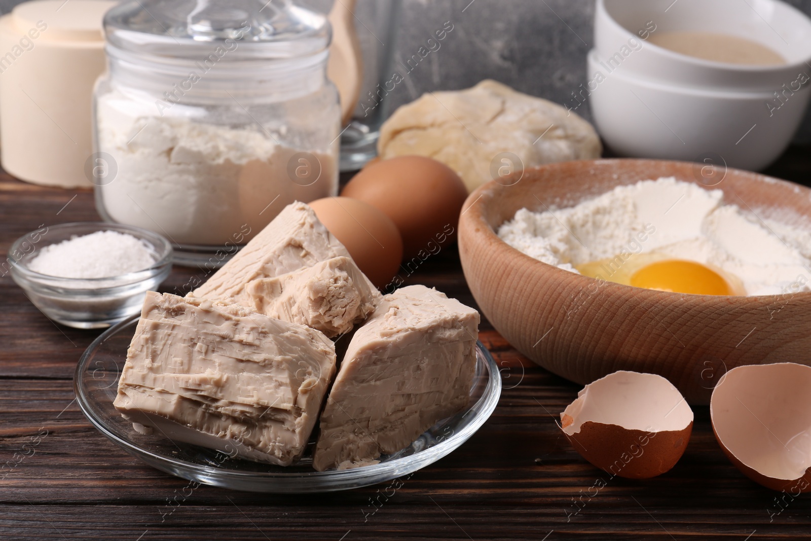 Photo of Compressed yeast, flour, salt, dough and eggs on wooden table