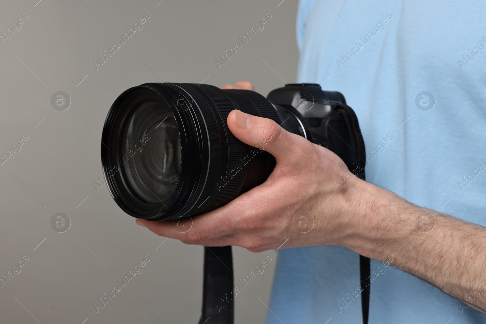 Photo of Photographer holding camera on grey background, closeup