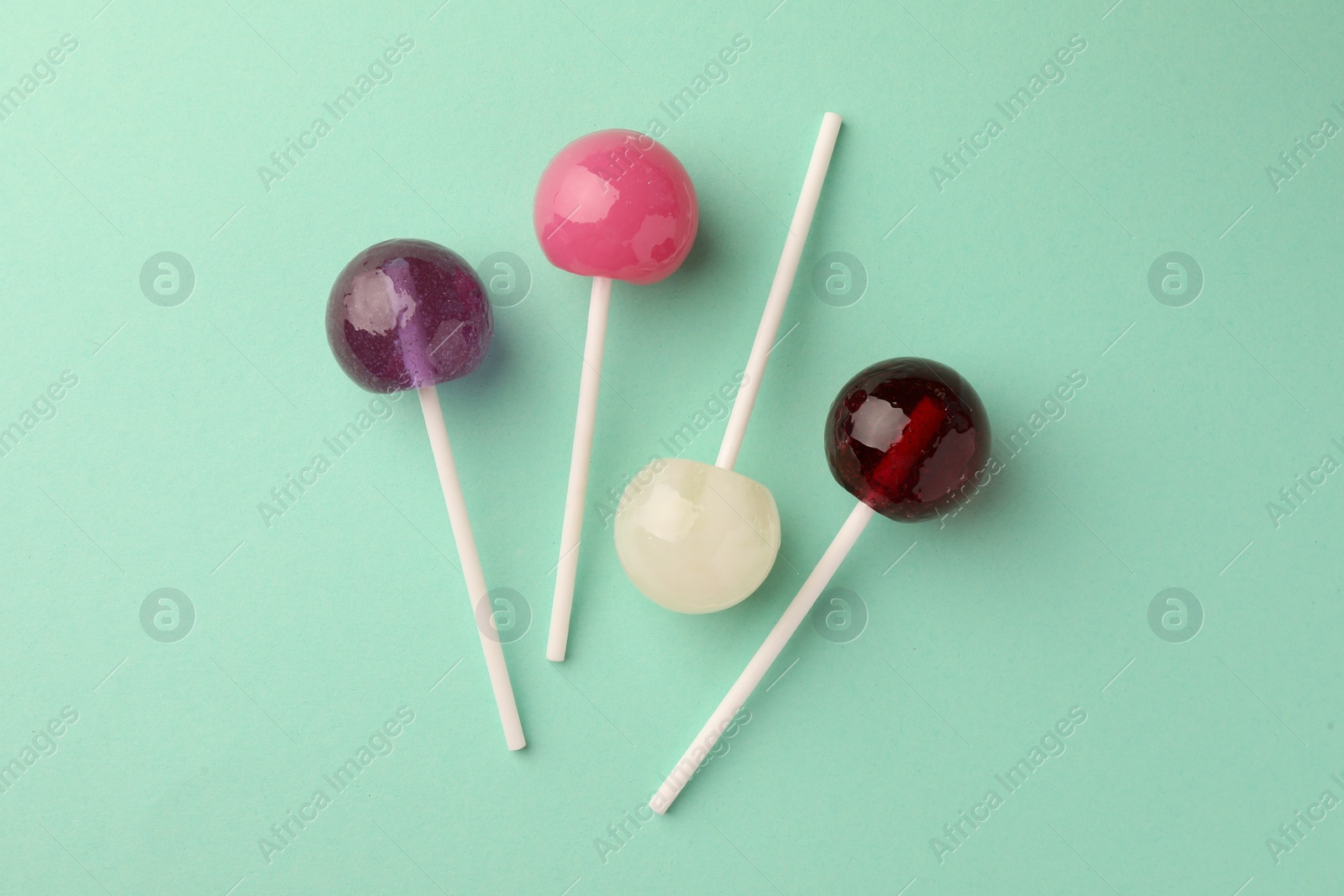 Photo of Tasty lollipops on turquoise background, flat lay