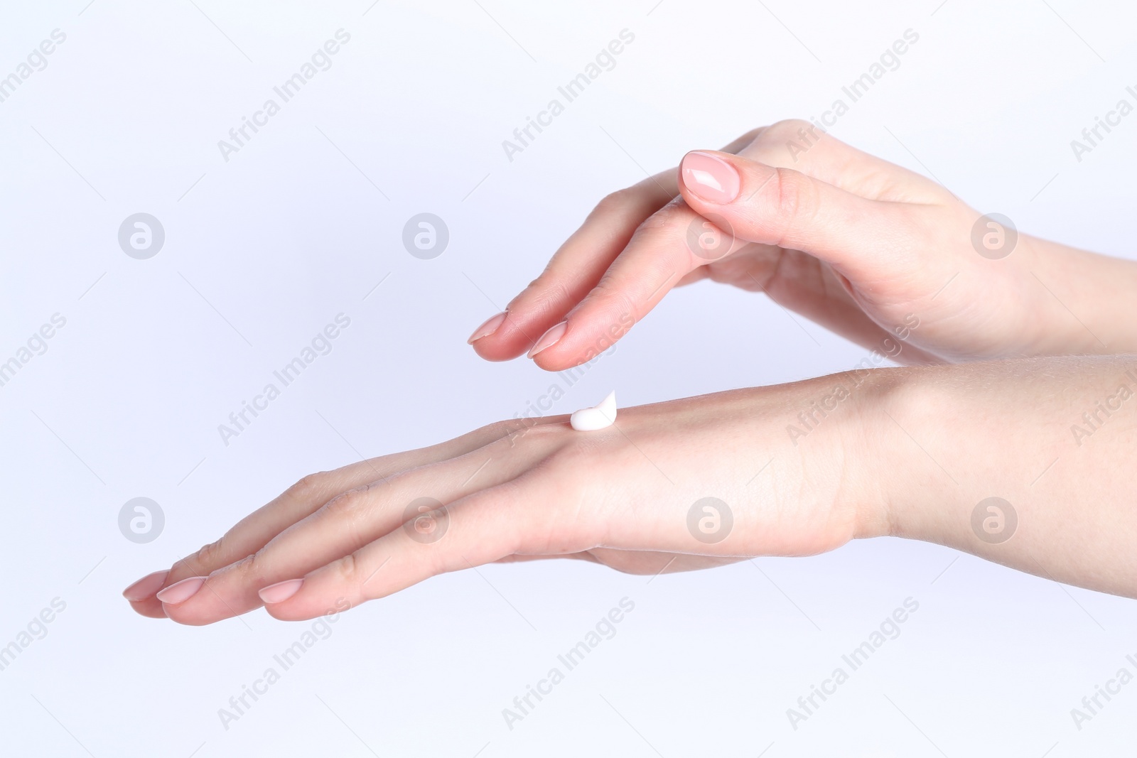 Photo of Woman applying cream on her hand against white background, closeup