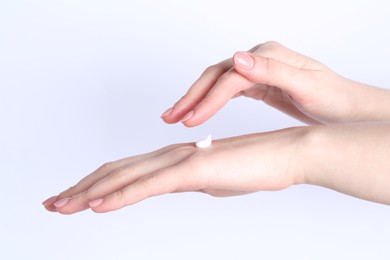 Woman applying cream on her hand against white background, closeup