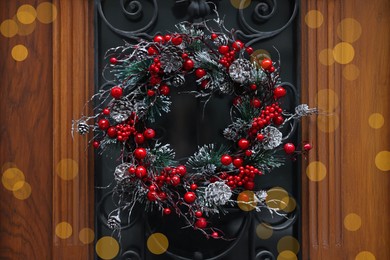 Beautiful Christmas wreath with berries and cones hanging on door