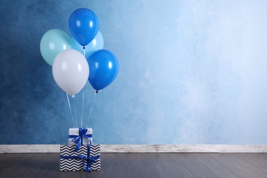 Photo of Bunch of color balloons and beautifully wrapped gift boxes near light blue wall indoors. Space for text