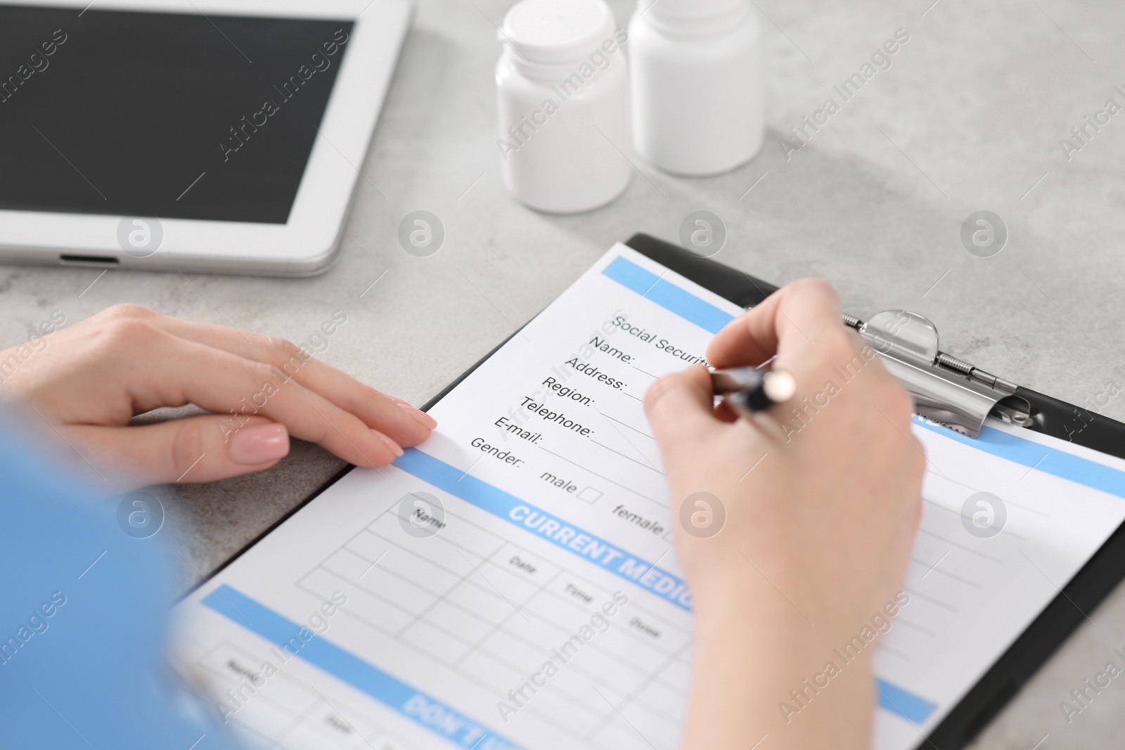 Photo of Doctor filling patient's medical card at table in clinic, closeup