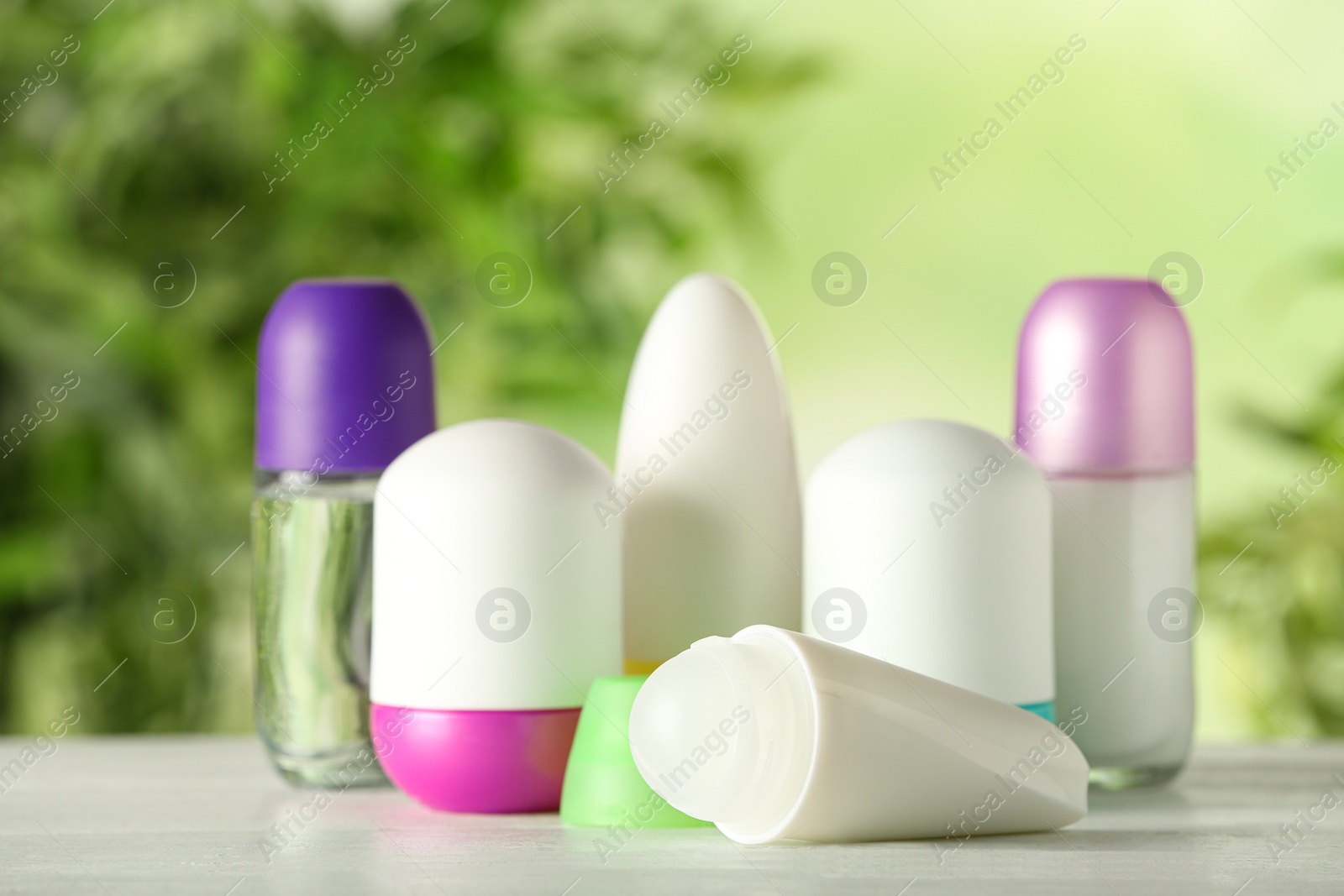 Photo of Different deodorants on white wooden table against blurred background