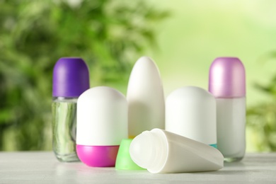 Photo of Different deodorants on white wooden table against blurred background