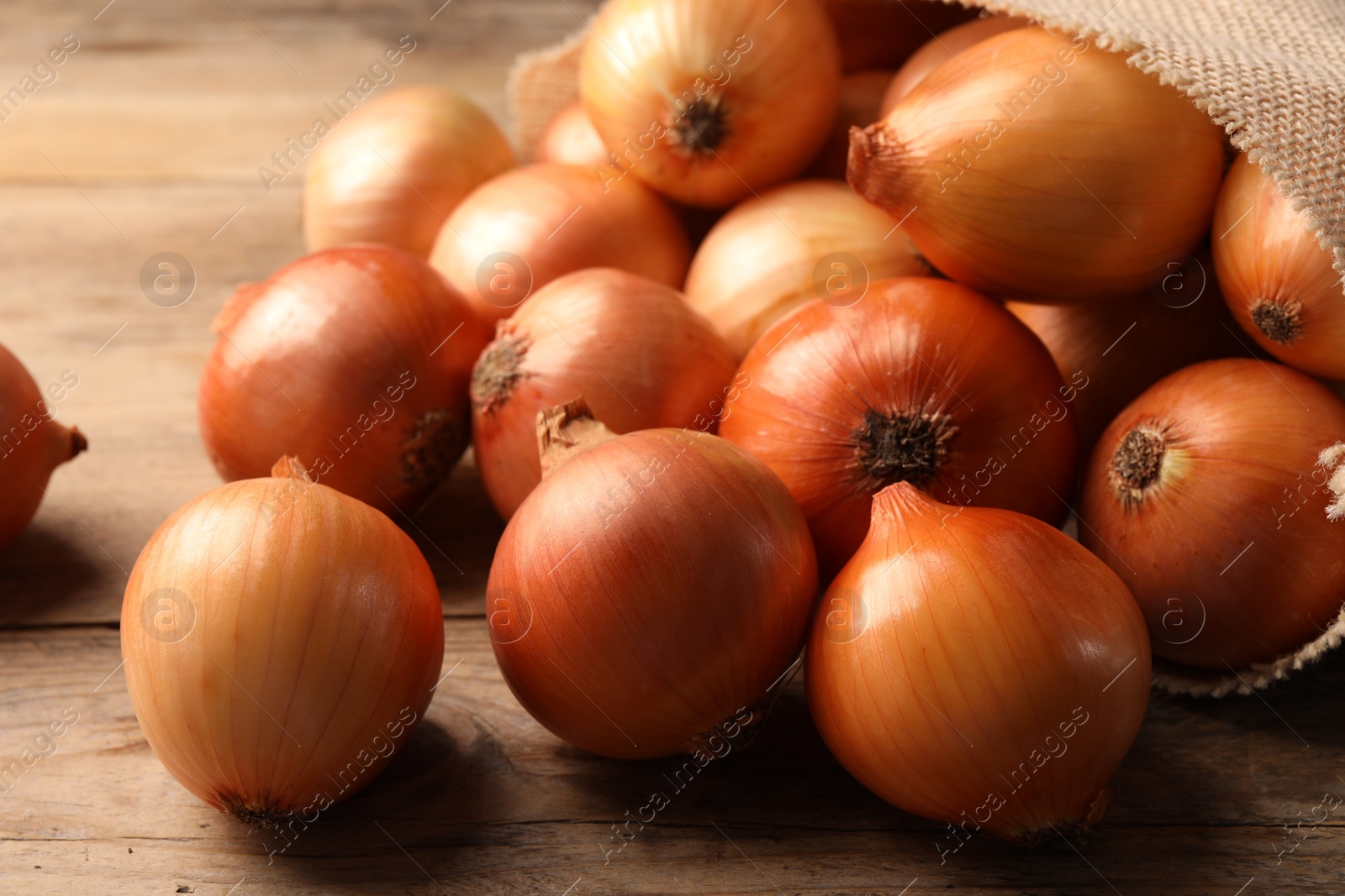 Photo of Many ripe onions on wooden table, closeup