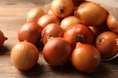 Many ripe onions on wooden table, closeup