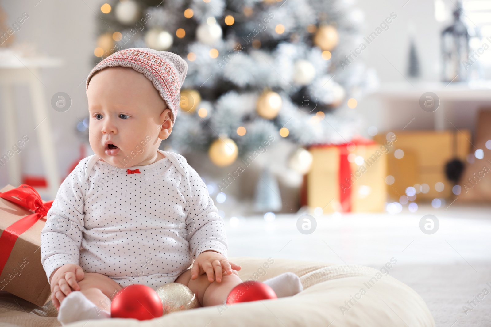 Photo of Little baby wearing cute hat indoors. First Christmas