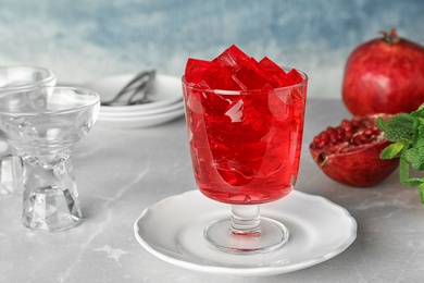 Composition with glass of pomegranate jelly on table against color background