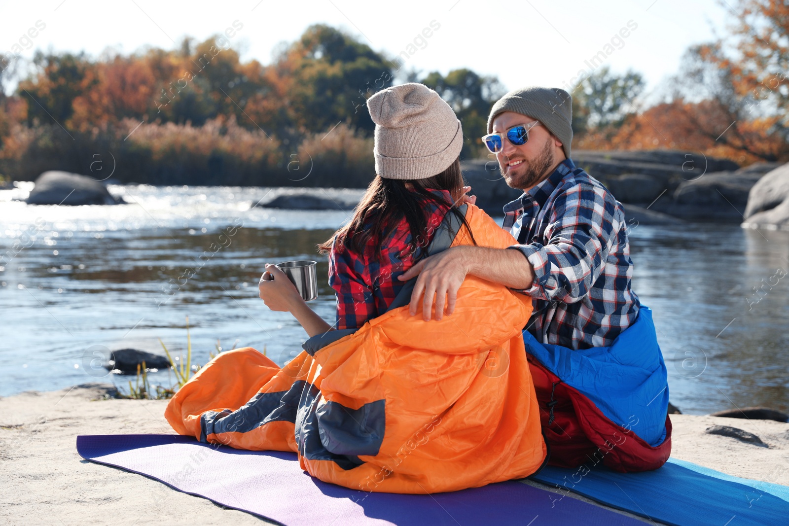 Photo of Campers sitting in sleeping bags on wild beach