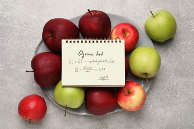 Photo of Notebook with calculated glycemic load for apples and fresh fruits on light grey textured table, top view