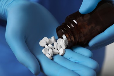 Doctor pouring pills from bottle, closeup view